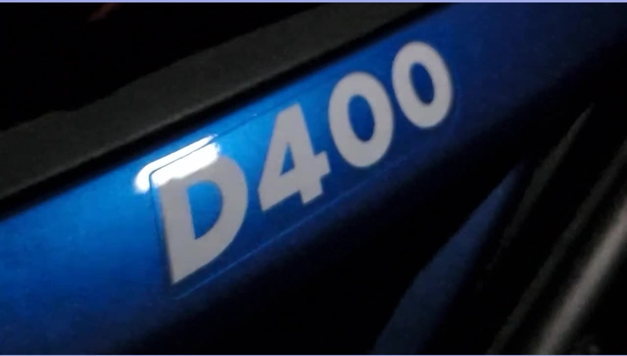 Close-up video frame of the D400 badge on a blue NRD electric motorcycle