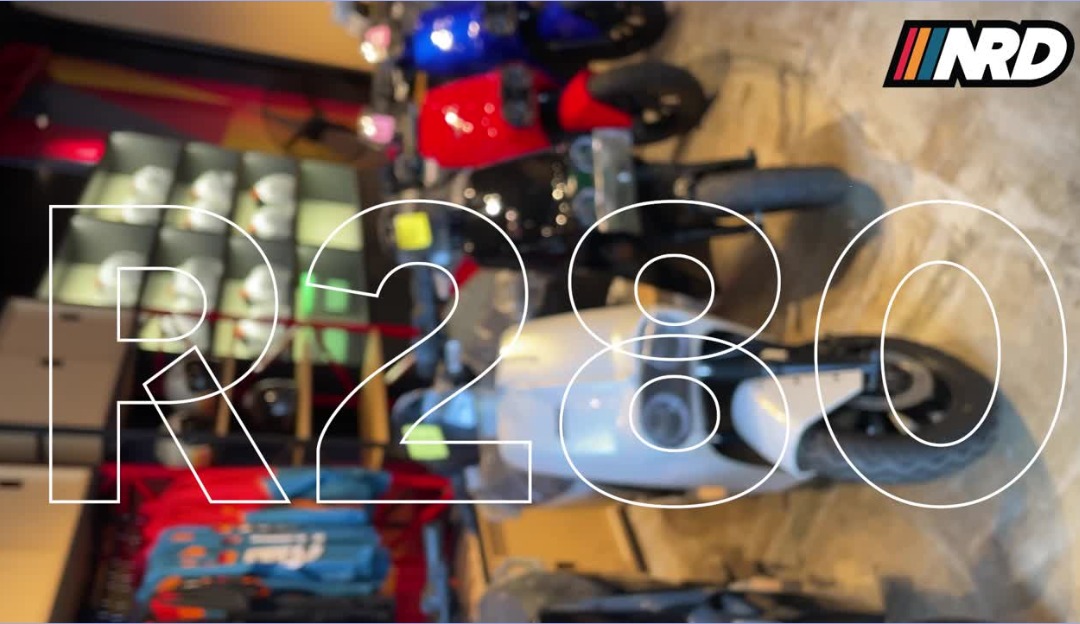 NRD product video frame with large outlined R280 typography over an electric motorcycle in a showroom